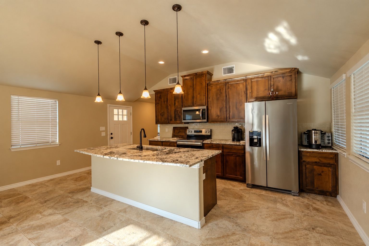 Clubhouse kitchen with a granite island, pendant lights and stainless appliances