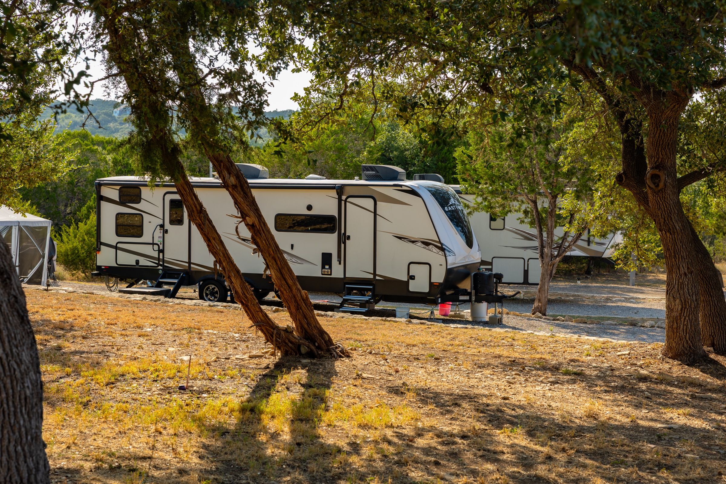 Travel trailer between oak trees