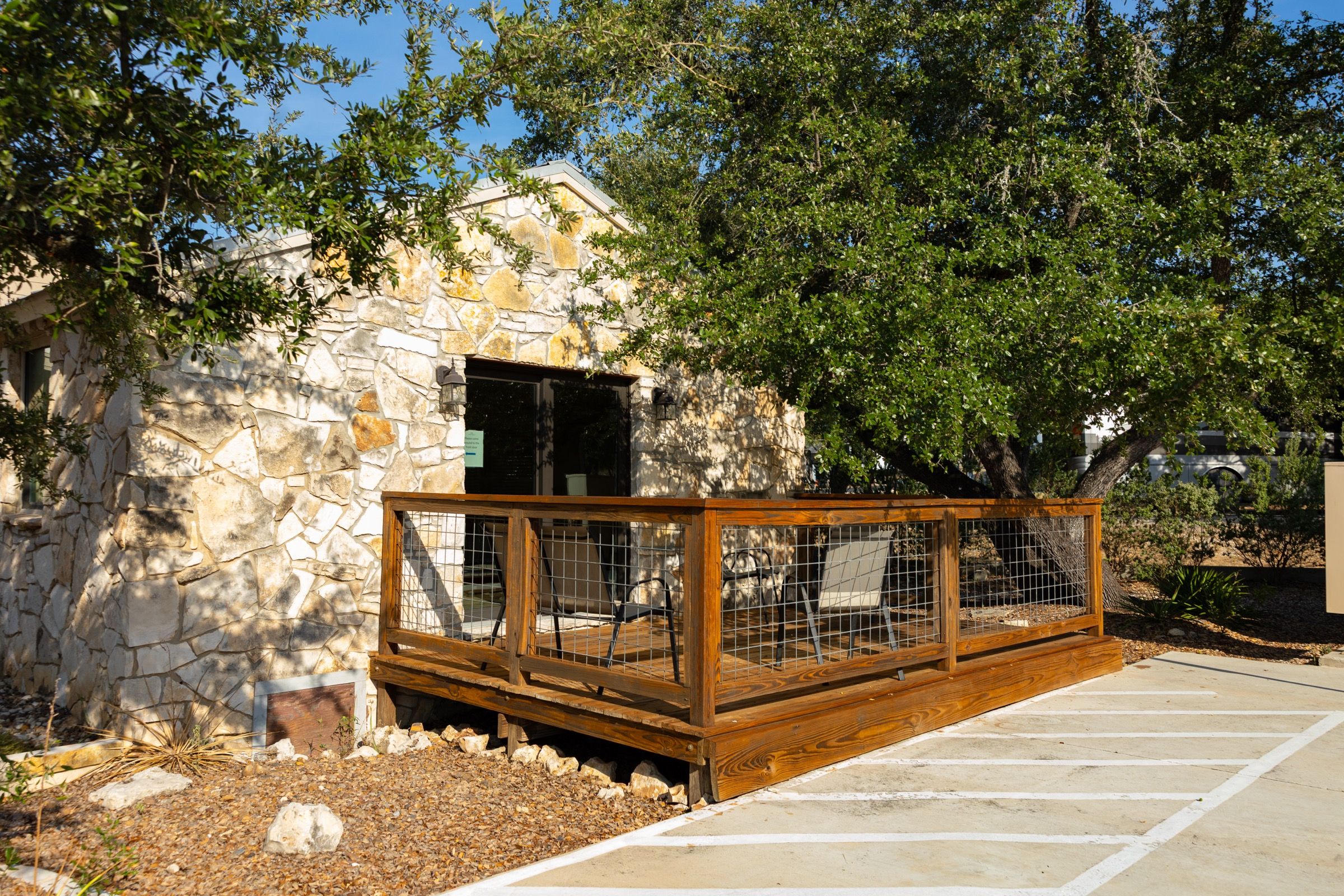 Stone building with a wooden deck under an oak